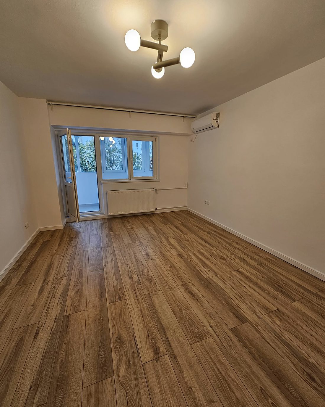 Garsonieră renovată la cheie: cameră cu parchet laminat nou și pereți albi