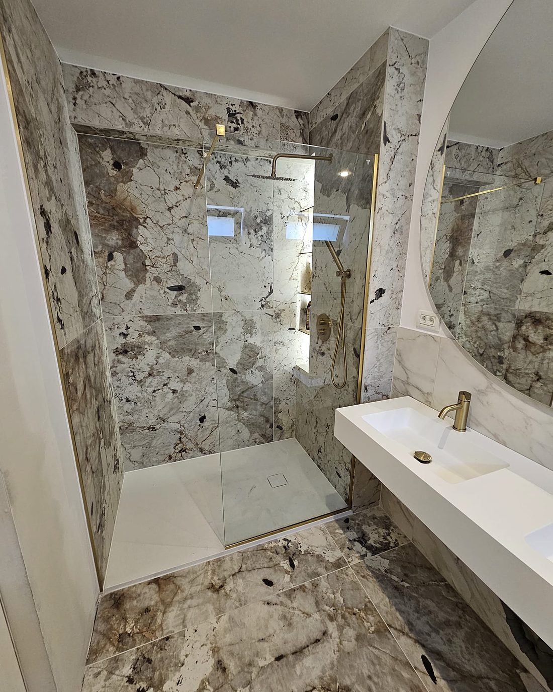 Baie renovată în Mogoșoaia: duș walk-in cu perete de sticlă, placări mari tip marmură și baterii aurii
