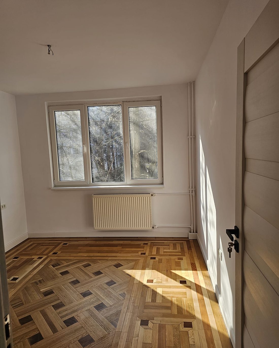 Cameră cu parchet montat în model clasic, cu chenar