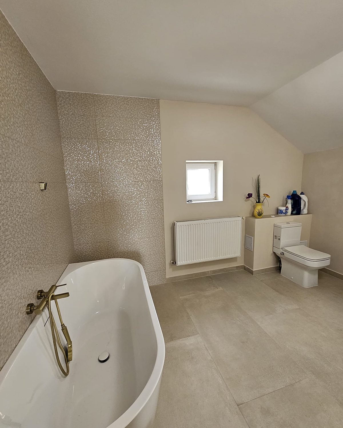 Baie la mansardă renovată de Mireclau: cadă freestanding cu baterie aurie și faianță decorativă
